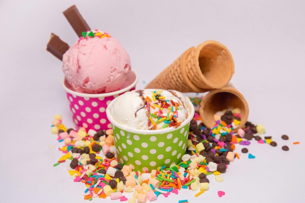 Delicious ice cream in vibrant cups with scattered sprinkles and waffle cones. Ice Cream Sundae Toppings