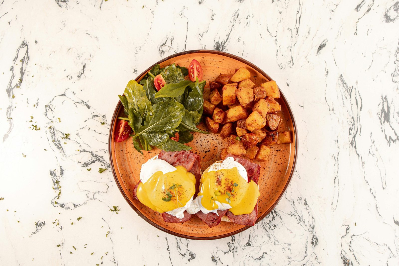 Savor this classic Eggs Benedict brunch with potatoes and a fresh salad.