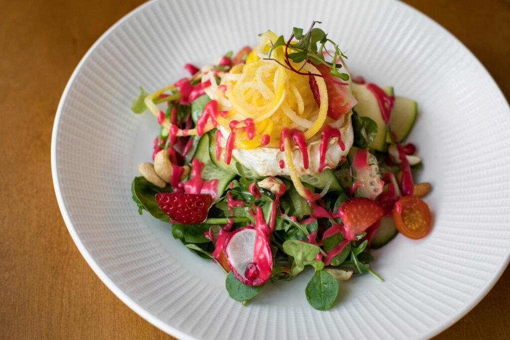 A delicious and colorful gourmet salad with vibrant dressing on a white plate .recipe for spinach salad with strawberries