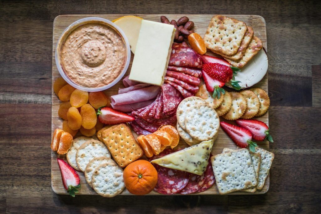 Delicious assortment of cheeses, cured meats, and fruits on a wooden platter.