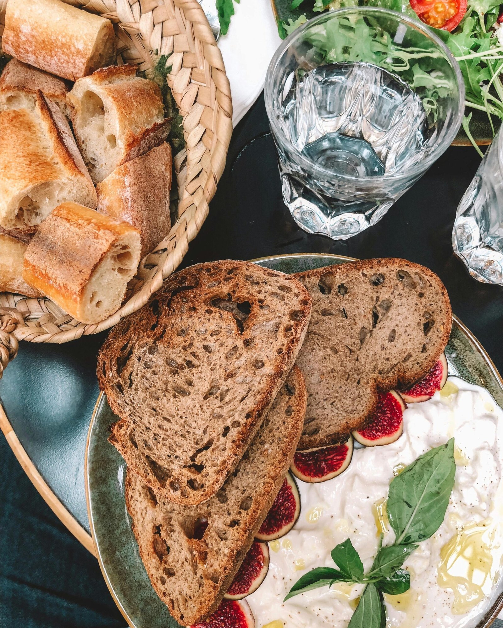 A delicious spread of artisanal bread with figs and greens in a French café setting.