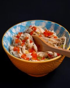 Delicious chicken salad with colorful peppers in a blue ceramic bowl.