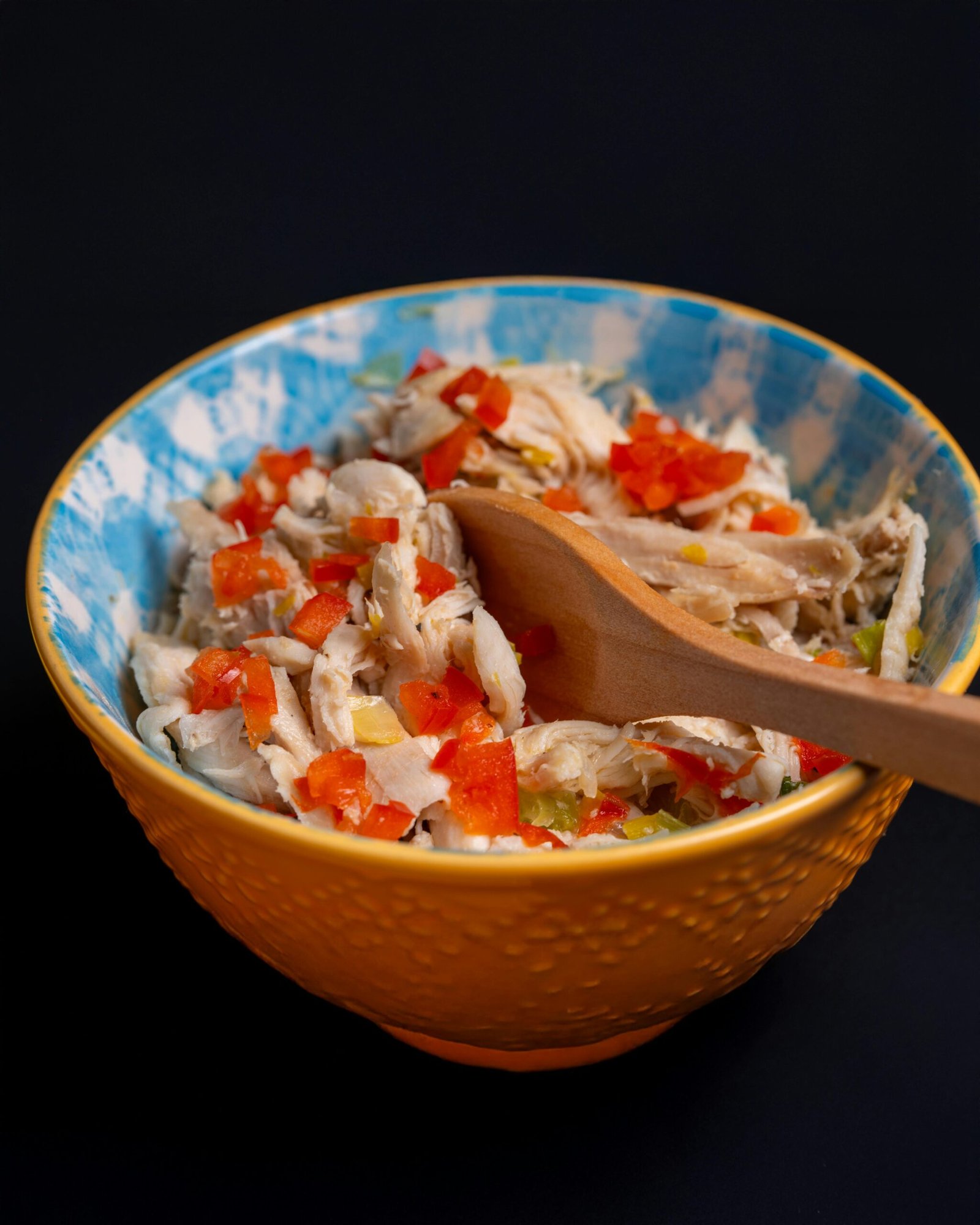 Delicious chicken salad with colorful peppers in a blue ceramic bowl.