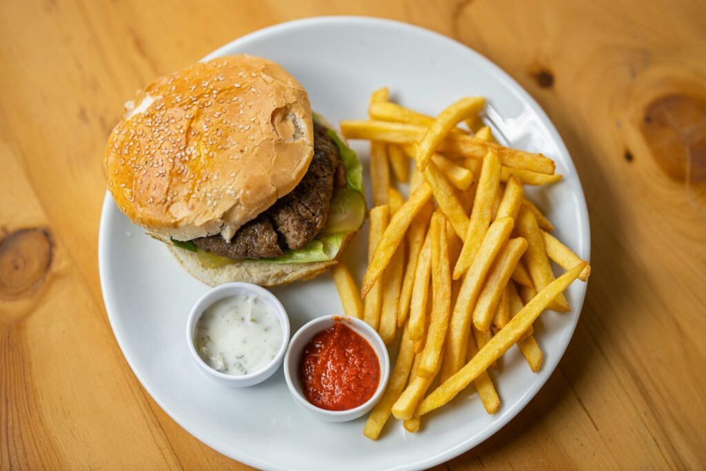 Mouthwatering cheeseburger and crispy fries served on a white plate, perfect for fast food lovers.