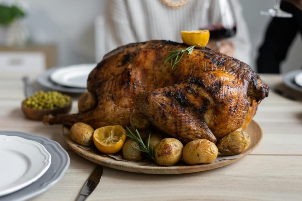 From above of big turkey roasted with lemon and potatoes on round wooden tray placed on table for celebrating Thanksgiving Day Turkey Dinner Recipes