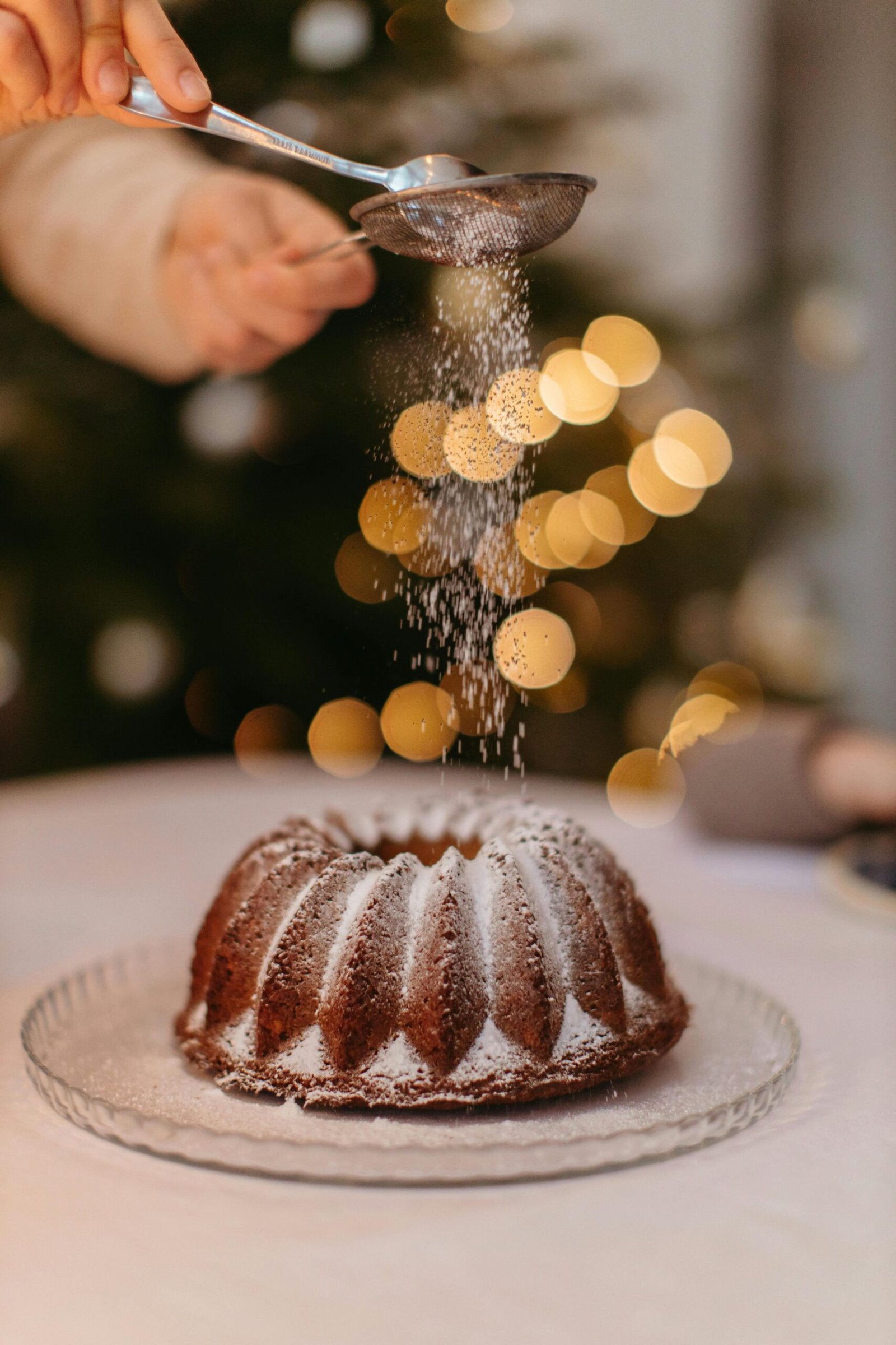 Delicious festive cake sprinkled with powdered sugar, set against a bokeh backdrop for a warm holiday feel.