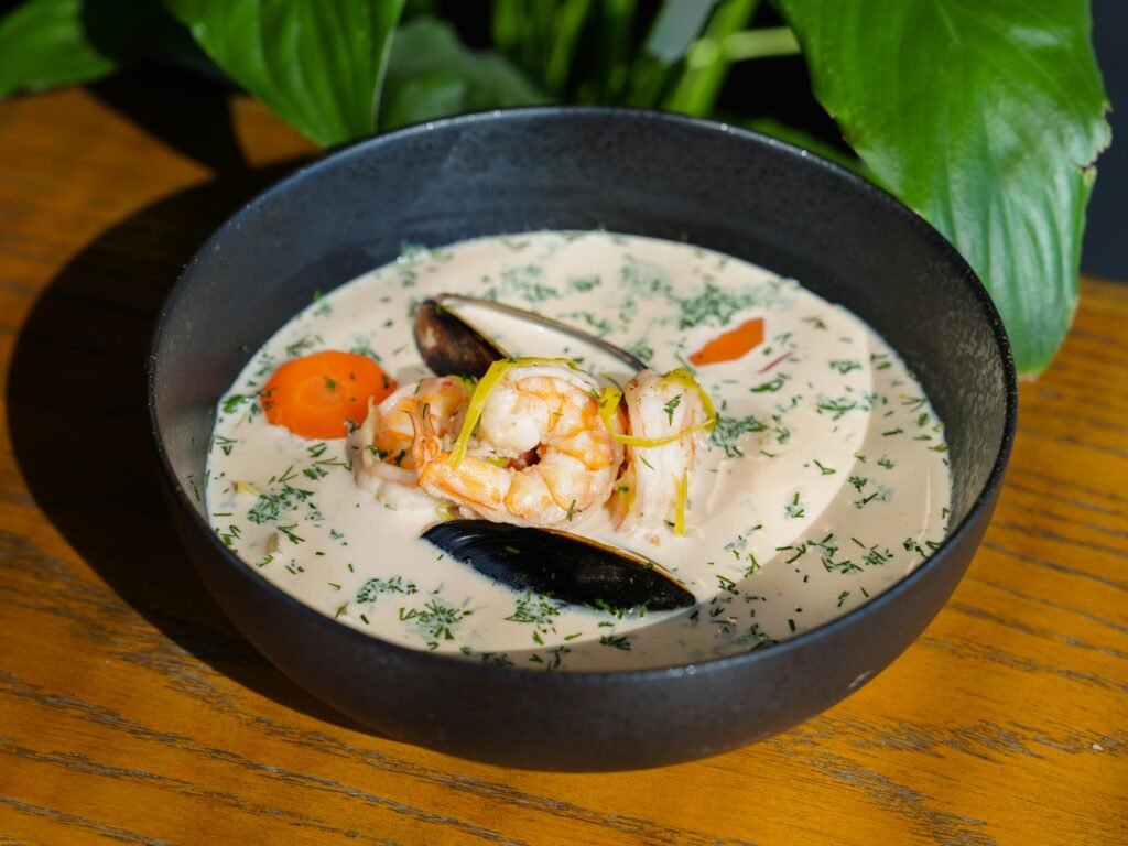 Close-up of a savory seafood chowder with shrimp and mussels in a black bowl. Classic Clam Chowder Recipe