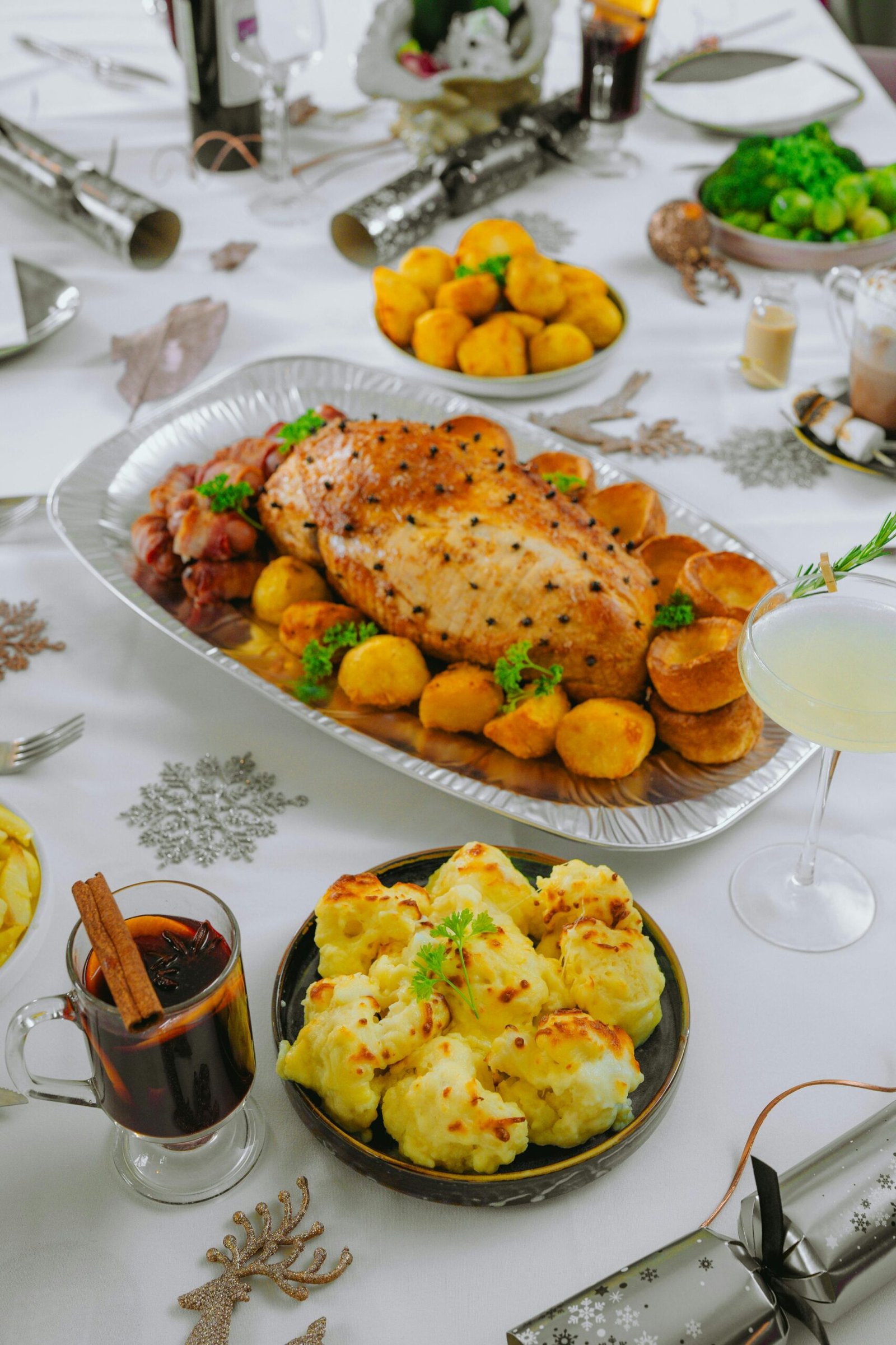 A delicious holiday meal featuring roast meat, potatoes, and festive decorations on a dining table.