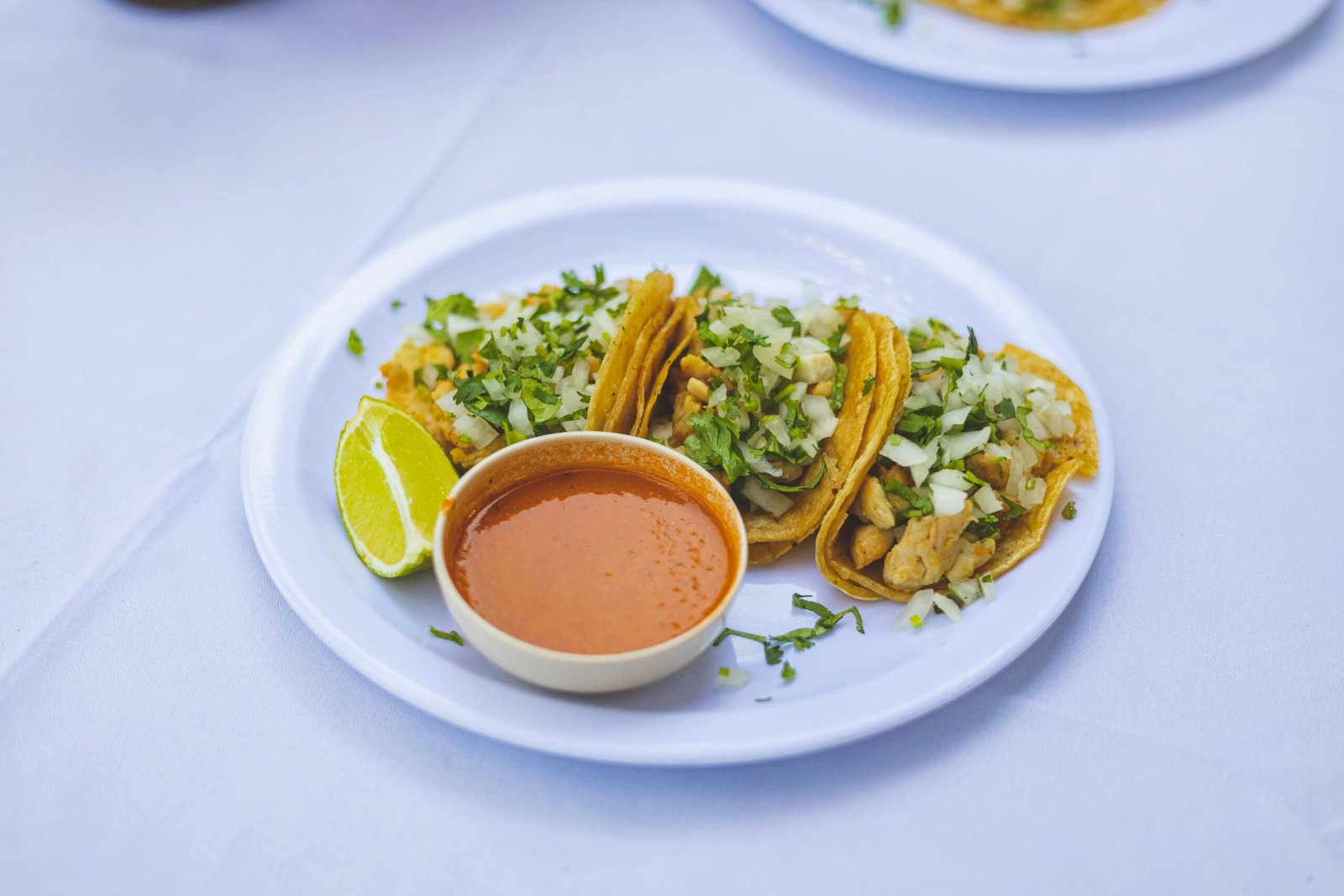 Delicious Mexican chicken tacos on a plate with salsa and fresh lime wedges.