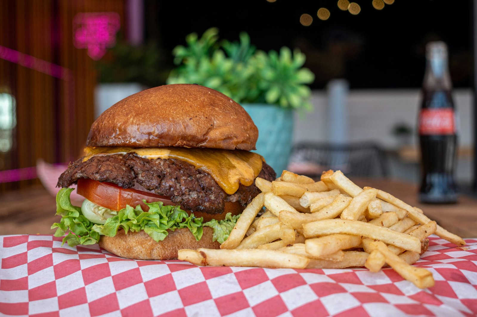 Delicious cheeseburger with fries served on a checkered paper in a vibrant diner setting.