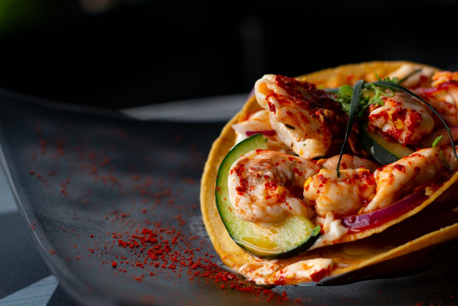 Mouthwatering spicy shrimp taco with fresh cucumber on a corn tortilla, perfect for food lovers.